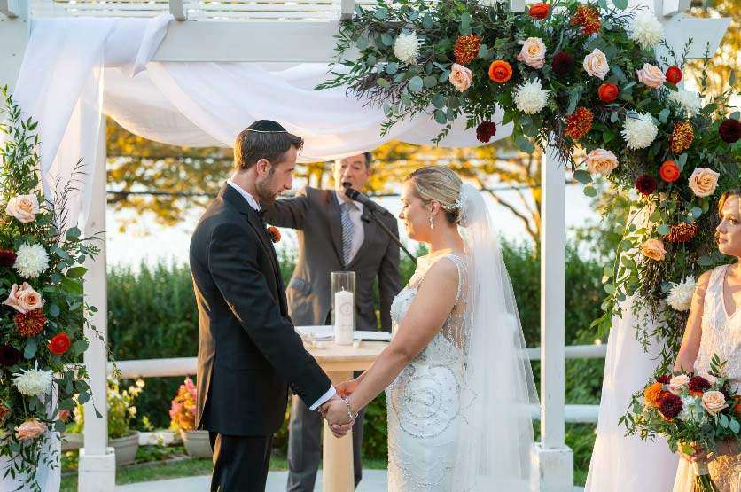 Bride and groom standing under the chuppah during a Jewish wedding ceremony officiated by Rabbi Ron Broden