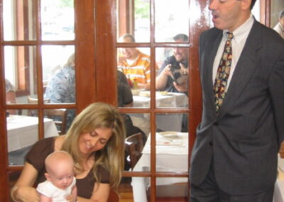 Rabbi Cantor Ron Broden holds a baby naming certificate while standing next to a mother and her newborn baby.