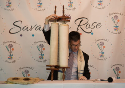 Rabbi Ron Broden holding a Torah scroll at a Bat Mitzvah ceremony.