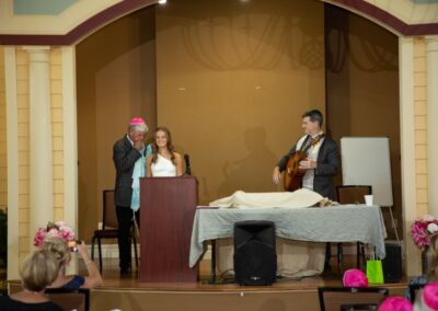 A young girl receives a shawl during her Bat Mitzvah ceremony, as Rabbi Cantor Ron Broden stands by in a synagogue.